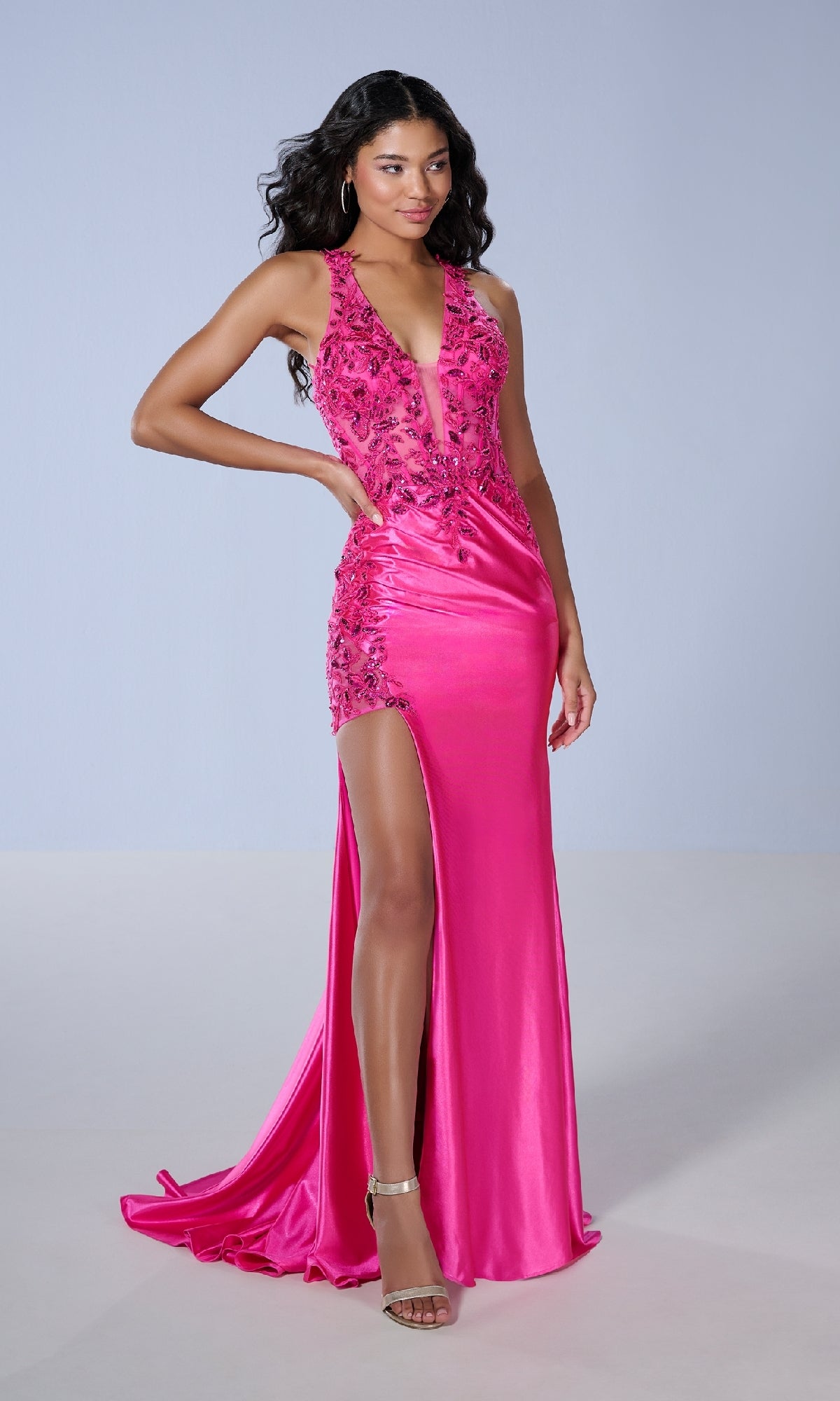 Wearing the Tiffany 16171, a bright pink satin long prom dress with a plunging v-neckline, floral embellishments, thigh-high slit, and open lace-up back, she completes her look with hoop earrings and strappy heels.